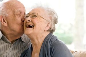 elderly husband kissing his wife on the cheek