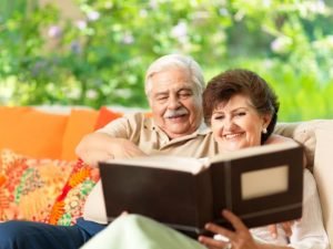 happy senior couple sitting together looking at a photo album